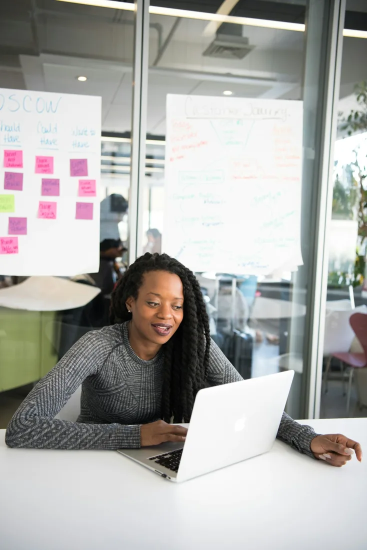 An entrepreneur working on her laptop beside customer-journey planning notes