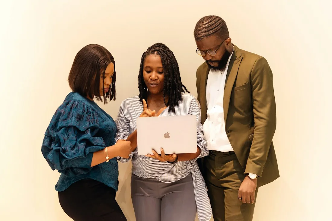 Three Nigerian professionals reviewing a laptop together